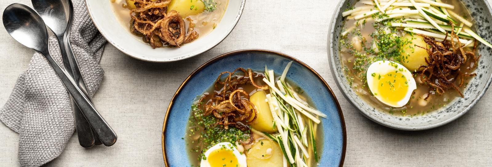 Nordisk ramensuppe med squash, hvide bønner, halve kogte æg og friterede løg